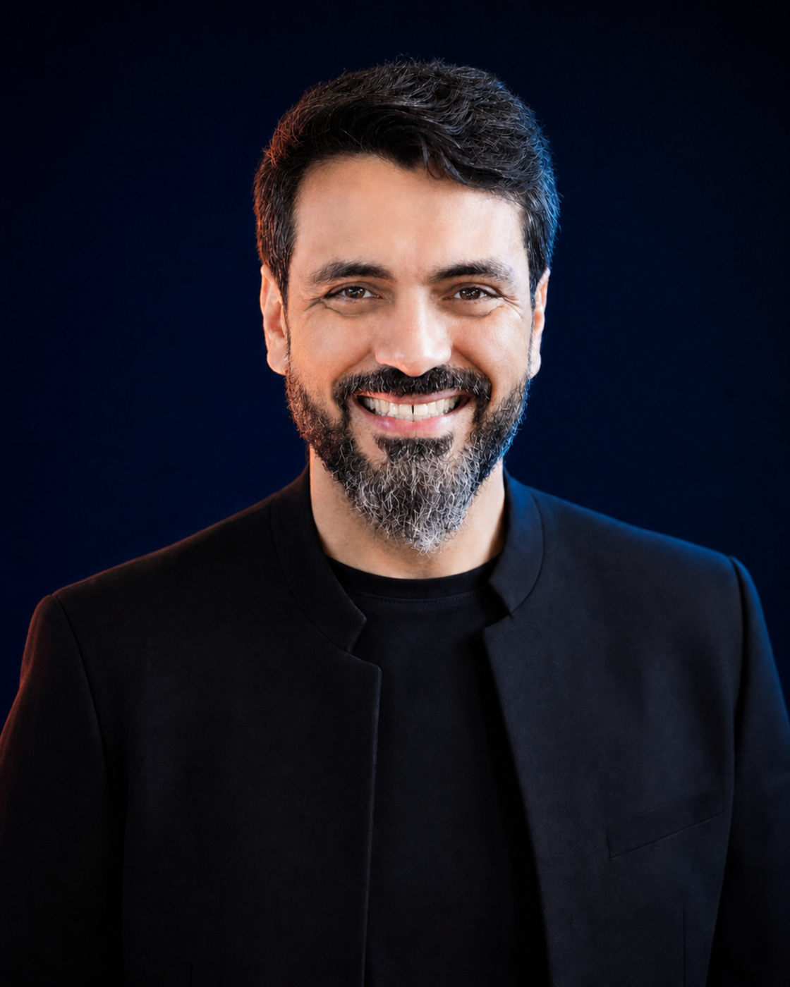 Retrato editorial de Wellington Dias, sorrindo, com cabelo escuro cuidadosamente penteado e barba sal-e-pimenta aparada, sobre fundo navy.